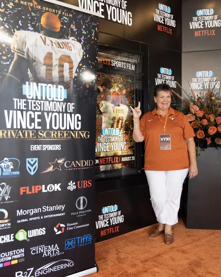 Guest arriving on the orange carpet beside the event sponsor board