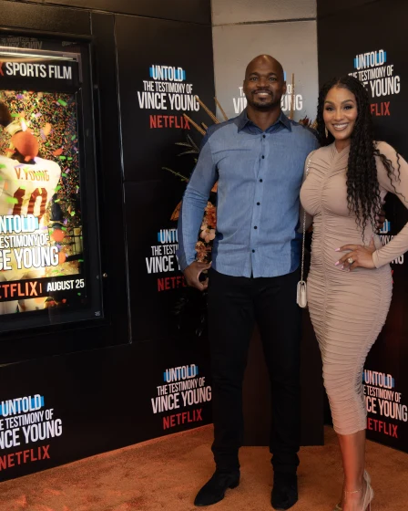 Two guests on the orange carpet beside the film's poster